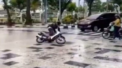 Pengendara sepeda motor terpeleset saat melintasi persimpangan Jalan Sudirman Medan.